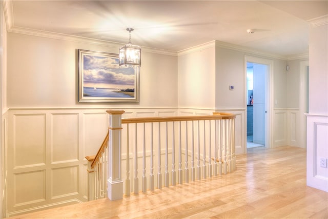 hall with light wood-type flooring, an inviting chandelier, and crown molding