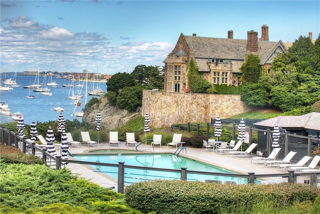 view of pool with a water view and a patio