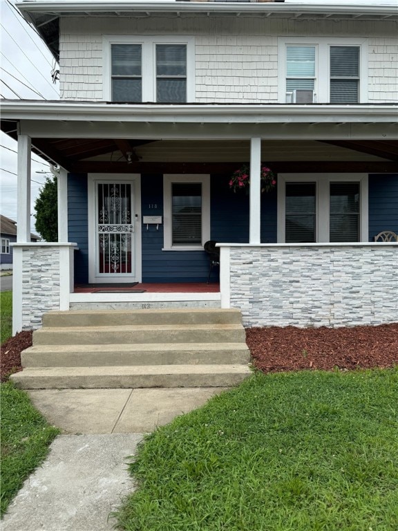 doorway to property with ceiling fan and a porch