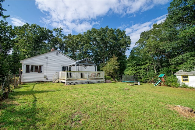 view of yard with a wooden deck, a trampoline, and a playground