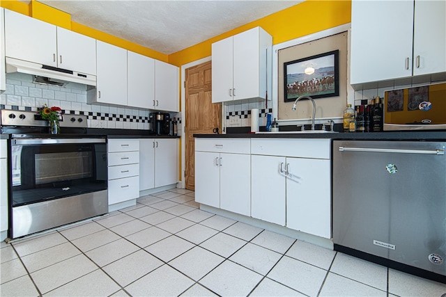 kitchen with light tile patterned floors, stainless steel appliances, sink, decorative backsplash, and white cabinets