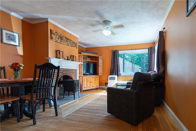 living room featuring ceiling fan, a fireplace, a textured ceiling, and light hardwood / wood-style flooring