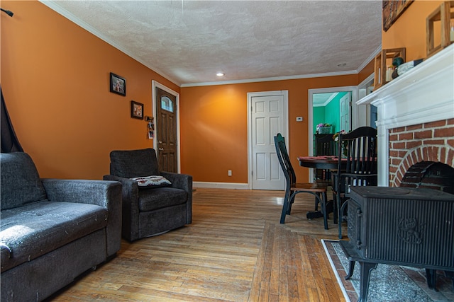 living room featuring a fireplace, light hardwood / wood-style floors, crown molding, and a textured ceiling