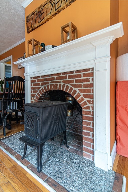 room details featuring wood-type flooring, a wood stove, crown molding, and a textured ceiling