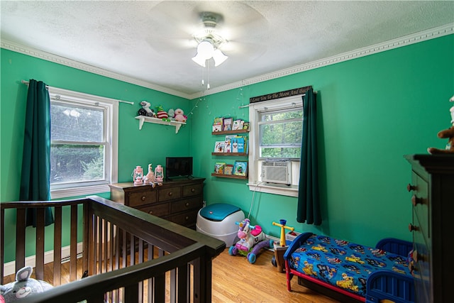 bedroom featuring cooling unit, hardwood / wood-style floors, ceiling fan, and a textured ceiling