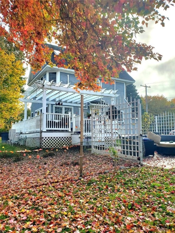 rear view of property featuring a deck and a pergola