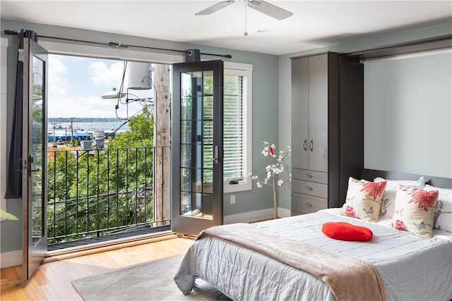 bedroom with wood-type flooring, a water view, ceiling fan, and access to exterior