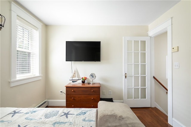 bedroom with dark hardwood / wood-style flooring and a baseboard heating unit