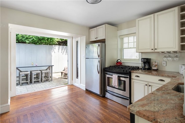 kitchen featuring stone countertops, wood finished floors, white cabinets, appliances with stainless steel finishes, and open shelves