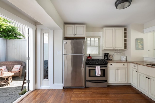 kitchen with white cabinetry, appliances with stainless steel finishes, light stone countertops, open shelves, and dark wood finished floors