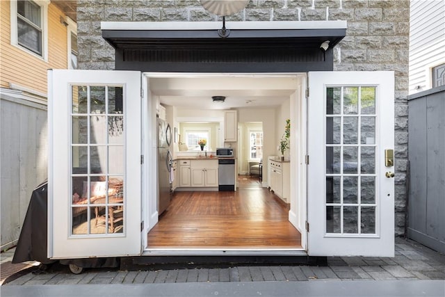 doorway to property featuring stone siding and fence