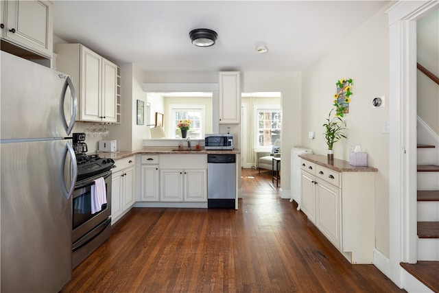 kitchen with appliances with stainless steel finishes, white cabinetry, dark hardwood / wood-style floors, and sink