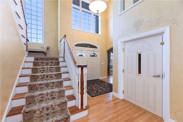 foyer with light hardwood / wood-style floors and a towering ceiling