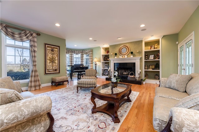 living room with a tiled fireplace, hardwood / wood-style floors, and built in features