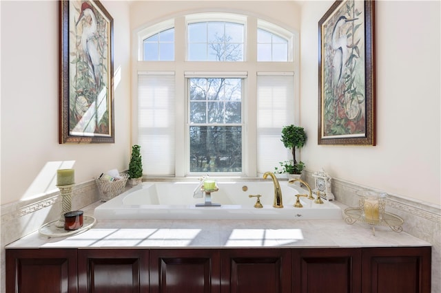 bathroom with a bath, dual sinks, and plenty of natural light