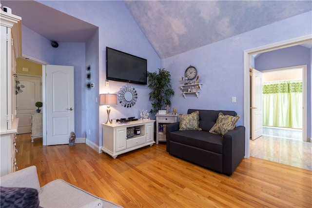 living room with light hardwood / wood-style floors and high vaulted ceiling