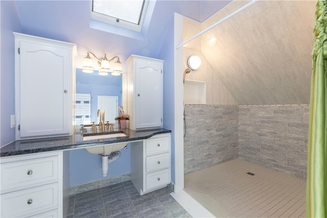 bathroom with lofted ceiling with skylight, sink, tile patterned flooring, and a tile shower