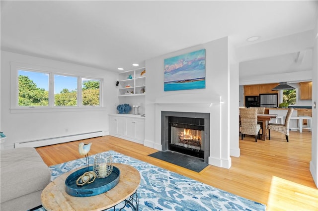 living room with a baseboard radiator, built in features, and light wood-type flooring