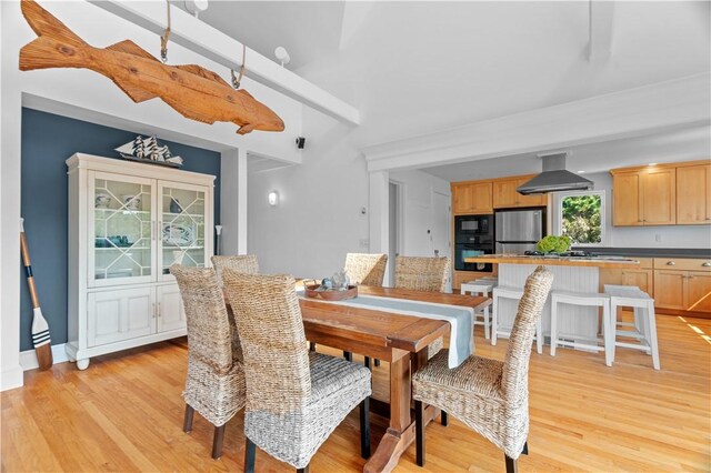 dining room featuring light wood-type flooring and beamed ceiling