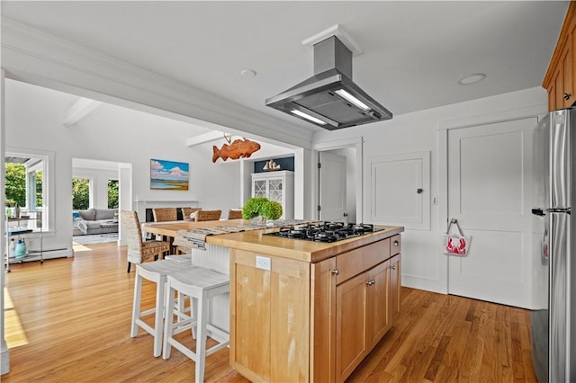 kitchen featuring black gas stovetop, butcher block counters, a kitchen island, island range hood, and beamed ceiling