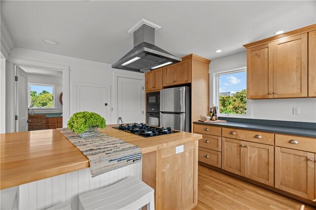 kitchen with black appliances, wood counters, island exhaust hood, and light hardwood / wood-style floors