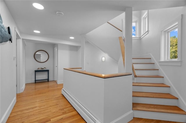 corridor featuring light hardwood / wood-style floors, baseboard heating, and plenty of natural light