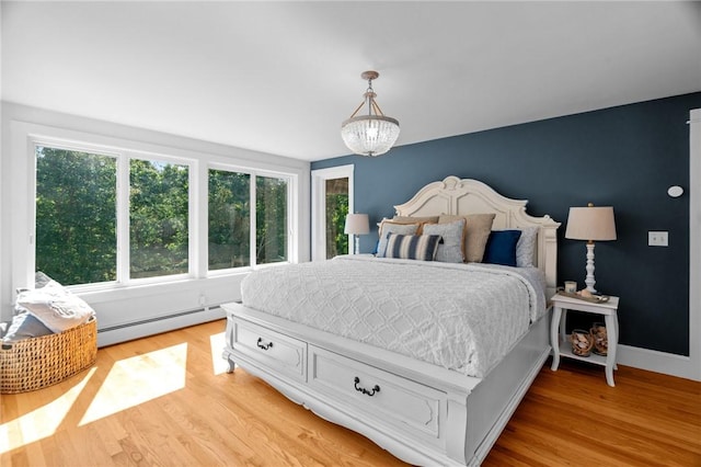 bedroom featuring baseboard heating, an inviting chandelier, and light wood-type flooring