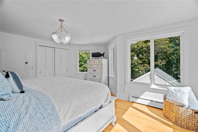 bedroom with a chandelier, light hardwood / wood-style flooring, and baseboard heating