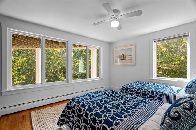 bedroom featuring ceiling fan, a baseboard radiator, and multiple windows