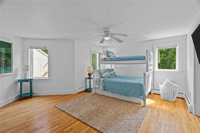 bedroom featuring ceiling fan, baseboard heating, and light wood-type flooring