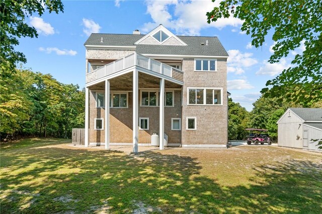 back of property featuring a balcony and a lawn