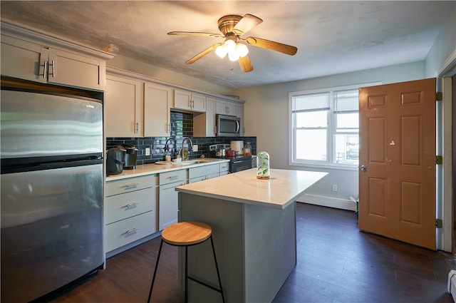 kitchen with dark wood-type flooring, sink, tasteful backsplash, stainless steel appliances, and ceiling fan