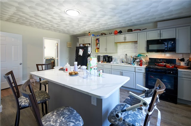 kitchen featuring gray cabinets, black appliances, a center island, and dark wood-type flooring