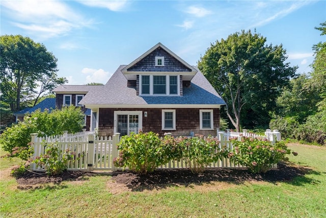 view of front facade with fence, a shingled roof, and a front lawn