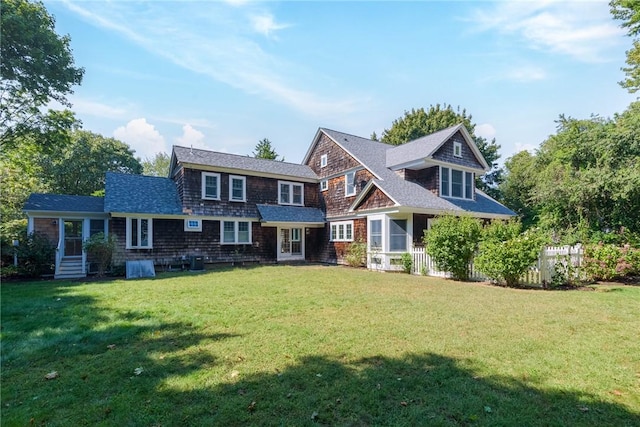 view of front of house featuring roof with shingles and a front yard