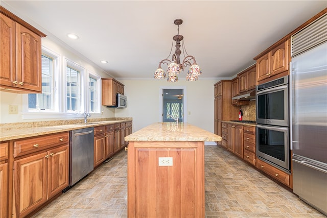 kitchen featuring light stone counters, a notable chandelier, a kitchen island, appliances with stainless steel finishes, and ornamental molding