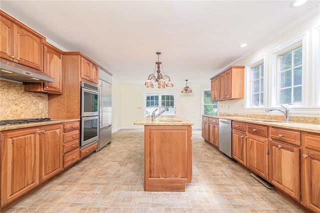 kitchen with a notable chandelier, a wealth of natural light, appliances with stainless steel finishes, and a kitchen island