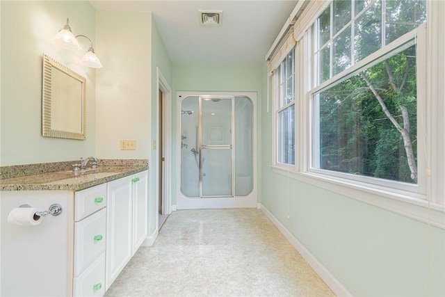 full bath with vanity, baseboards, a stall shower, and visible vents