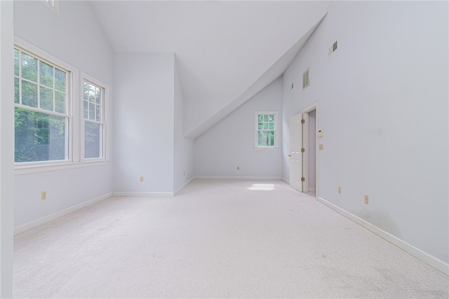 additional living space featuring light colored carpet and high vaulted ceiling