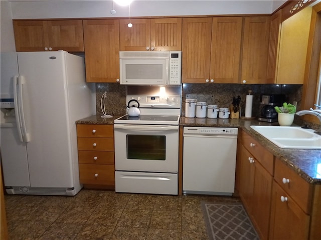 kitchen featuring dark stone counters, sink, white appliances, and decorative backsplash