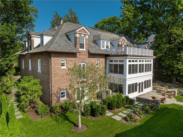 back of house with a lawn, a balcony, a sunroom, and a patio area