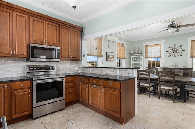 kitchen with kitchen peninsula, stainless steel appliances, crown molding, dark stone countertops, and ceiling fan