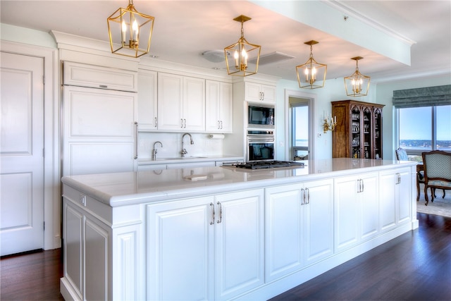 kitchen featuring appliances with stainless steel finishes, sink, pendant lighting, white cabinets, and a center island