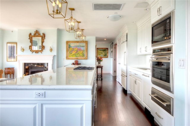 kitchen featuring pendant lighting, built in appliances, a kitchen island, dark hardwood / wood-style flooring, and white cabinetry