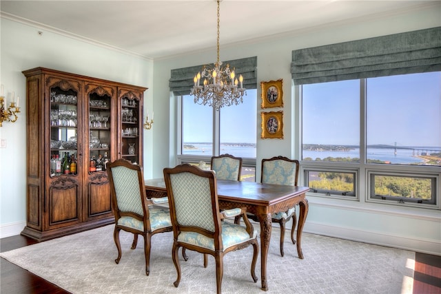 dining area featuring hardwood / wood-style flooring, a water view, a chandelier, and ornamental molding