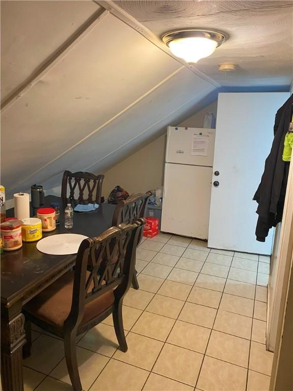 additional living space featuring light tile patterned floors and vaulted ceiling