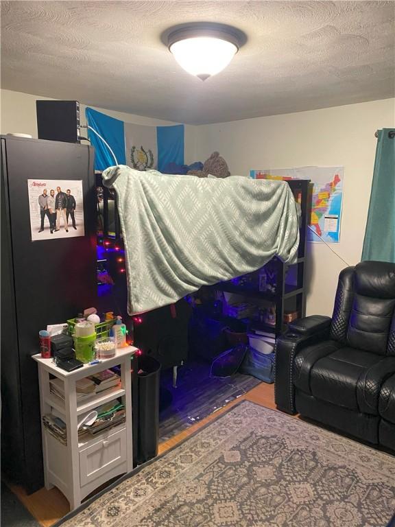 bedroom with black refrigerator and a textured ceiling