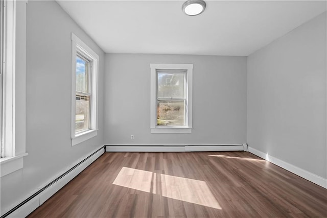 empty room featuring baseboard heating and dark hardwood / wood-style flooring