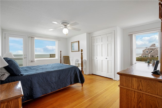 bedroom with a textured ceiling, wood-type flooring, ceiling fan, and a closet