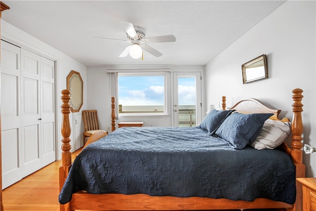 bedroom with ceiling fan, a textured ceiling, light wood-type flooring, and a closet